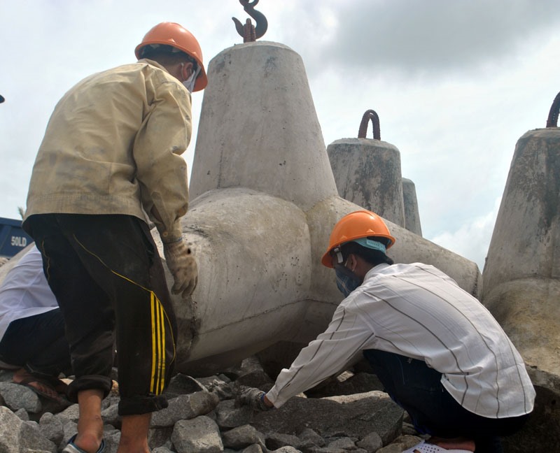 Công nhân thi công theo con nước, nên thường xuyên làm việc vào ban đêm (ảnh trái). Ảnh: NHẬT HỒ