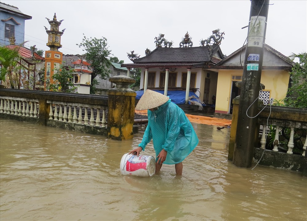 Người dân ở thôn Hưng Nhơn (Hải Hòa) tận dụng nước lũ để lau rửa lớp bùn non tràn vào nhà. Ảnh: Hưng Thơ.