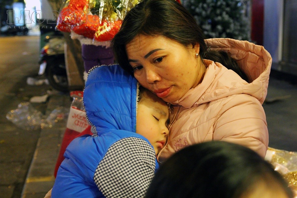 Một bé trai khác ngủ trong vòng tay của mẹ khi đang đi chơi Noel trên phố Hàng Mã.