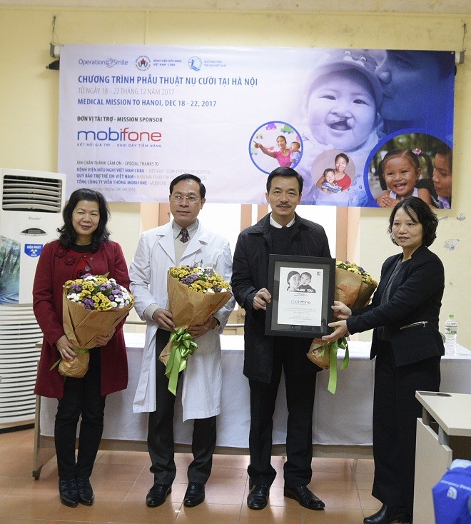 Ông Nguyễn Mạnh Hùng, Phó TGĐ Tổng công ty Viễn thông MobiFone nhận hoa và bằng từ đại diện Operation Smile Việt Nam, bà Nguyễn Thị Hải Đức, Giám đốc chương trình Operation Smile Việt Nam