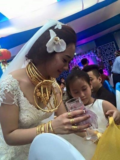 Cổ và tay cô dâu đeo rất nhiều vàng.