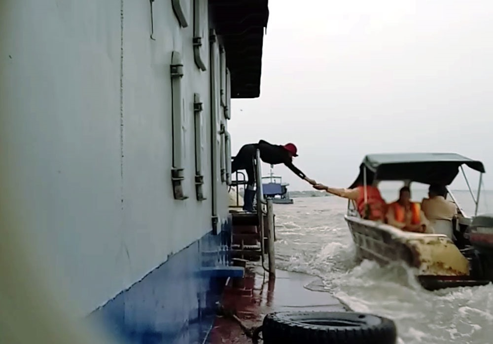 Một pha áp mạn và đưa-nhận nhanh như cắt giữa người trên tàu và 3 người trong trang phục CSGT.