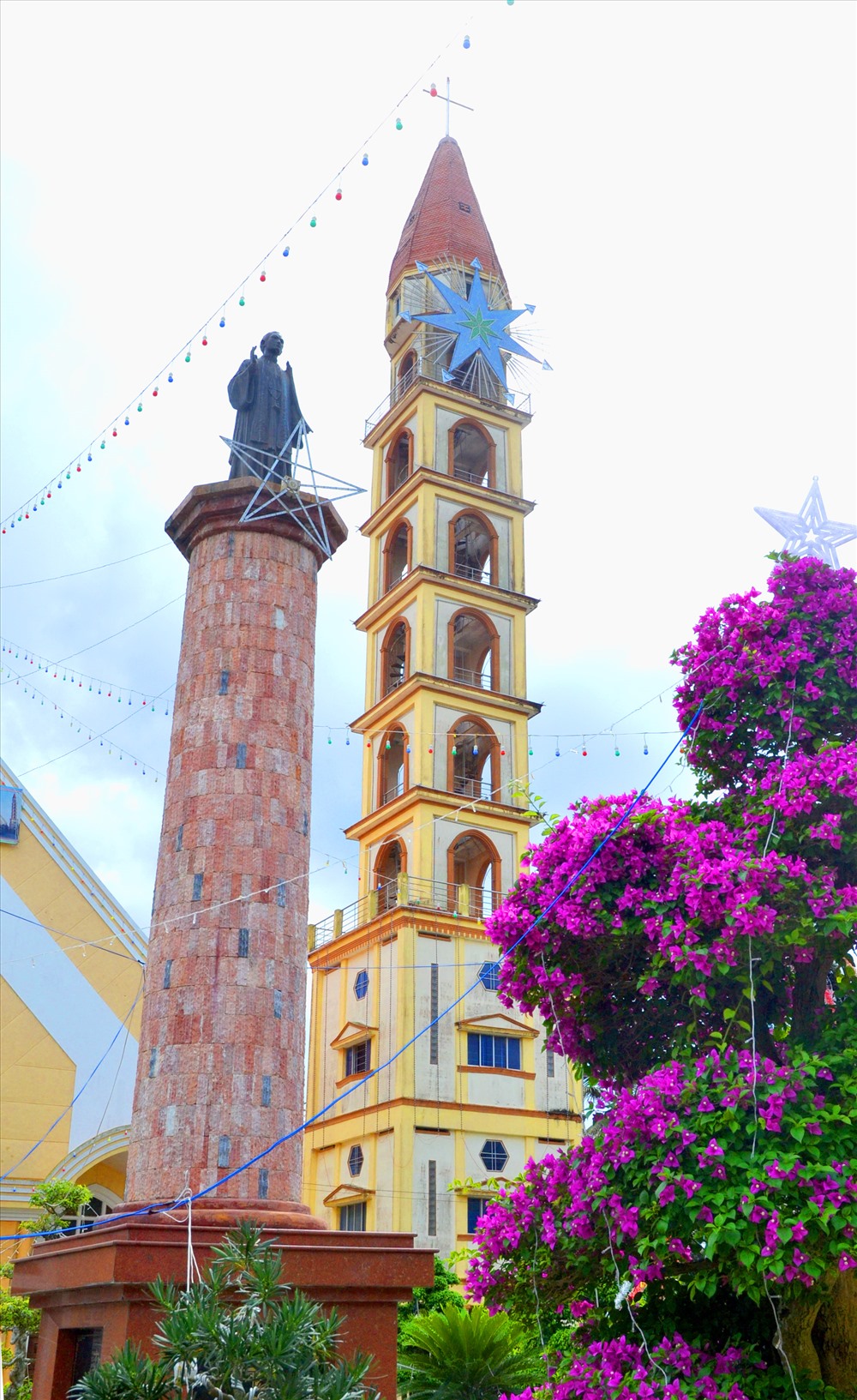 Gần tháp chuông là tượng của Thánh Phan Văn Minh (1815- 1858), người con  của đất Cái Mơn- thu phong linh mục 1846, hiển thánh  năm 1988. (Ảnh: Lục Tùng)