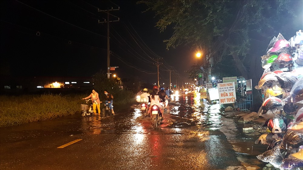 Tại đường Hồ Học Lãm, khoảng 18h20 nước từ dưới cống và rạch Bà Tiếng bắt đầu tràn lên mặt đường. Ảnh: Trường Sơn