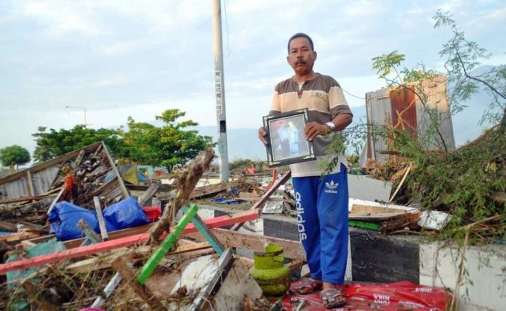 Một người đàn ông cầm di ảnh của người thân. Ảnh: Getty Images