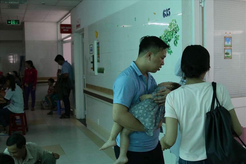 Hai vợ chồng đang bế con mắc bệnh khá nặng chờ vào giường nằm. Ảnh: BT