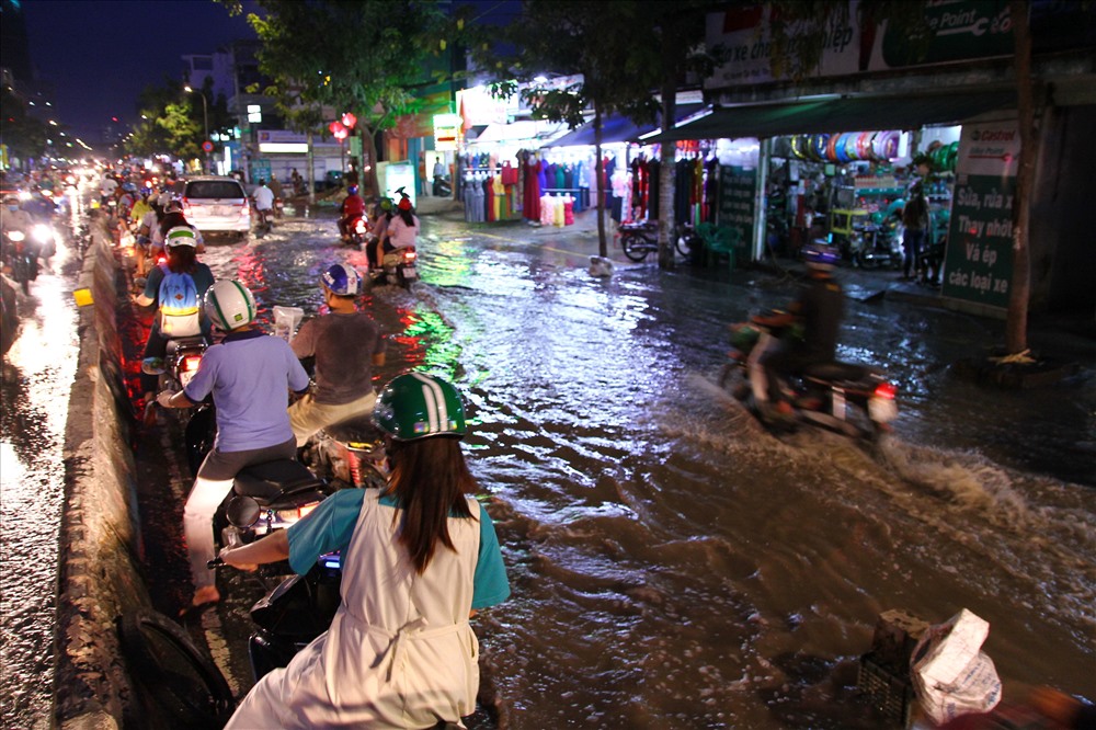 Người dân đi chuyển sát vào con lươn để né đoạn đường ngập nước.