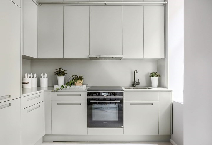 Bếp nấu màu xám đặt cạnh cửa để lấy ánh sáng, tủ bếp không tay nắm mà sử dụng hệ thống đóng mở bằng thanh giảm chấn tiết kiệm đáng kể không gian đồng thời đảm bảo an toàn cho người nội trợ khi di chuyển.