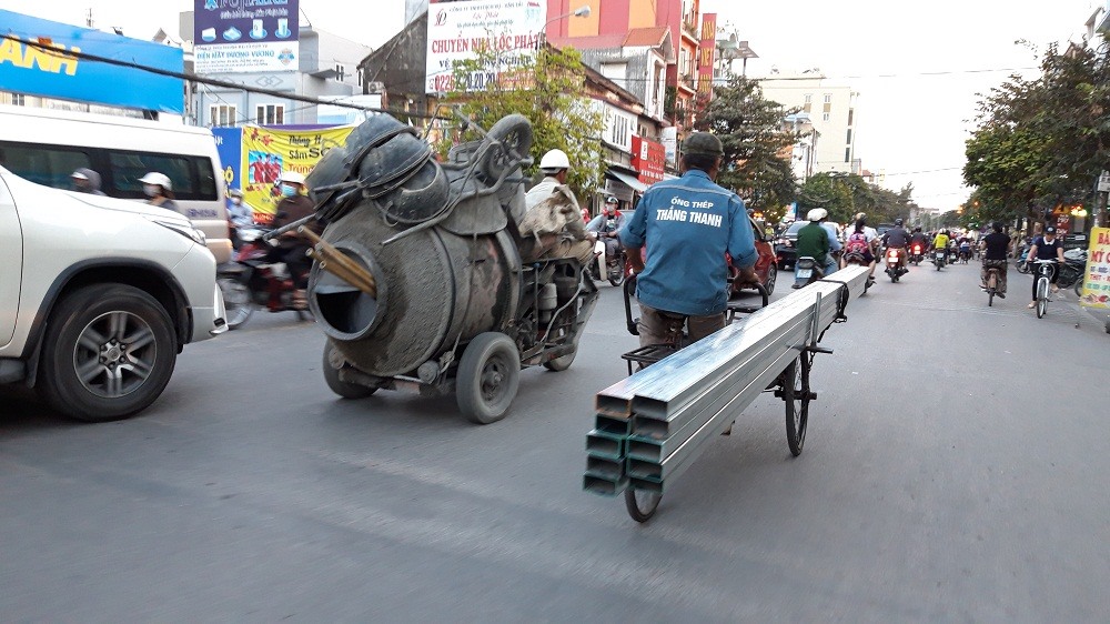 Các phương tiện chở vật liệu cồng kềnh di chuyển nhưng không được che chắn gây nguy hiểm cho người đi đường. Ảnh: PV.