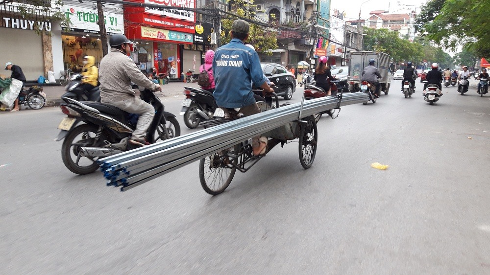 Xe xích lô chở ống thép dài hoành hành trên phố Tô Hiệu. Ảnh: PV.