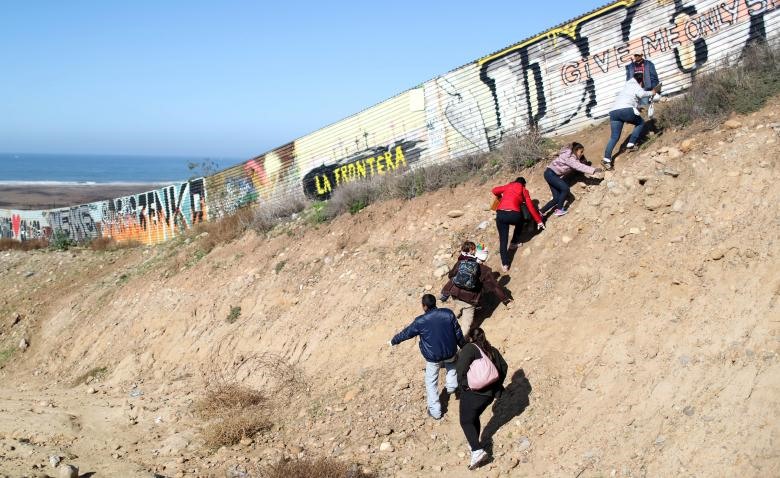 Những người di cư từ Honduras đang cố gắng vượt qua hàng rào biên giới ở Tijuana, Mexico để đến Mỹ.