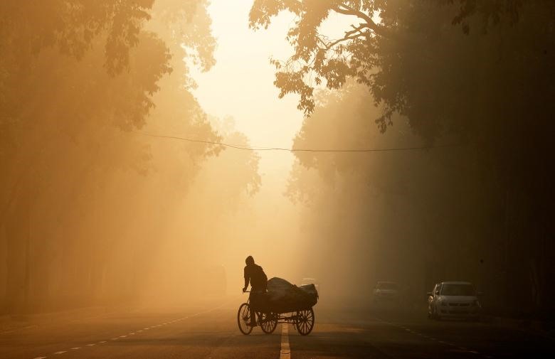 Một người đàn ông đi xe kéo vào một buổi sáng đầy sương mù ở New Delhi, Ấn Độ.