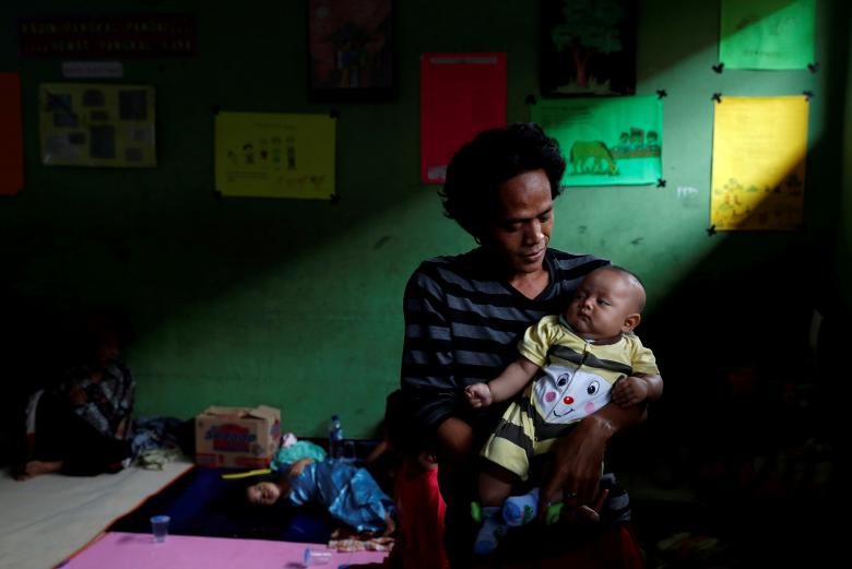 Một người đàn ông bế đứa con của mình đang trú ẩn trong một ngôi trường ở Labuhan, tỉnh Banten, Indonesia sau khi thảm họa sóng thần núi lửa xảy ra.
