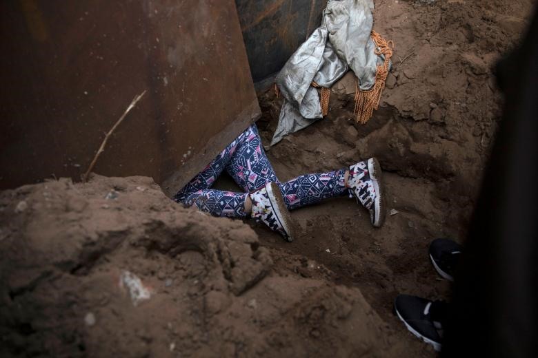 Một số người quyết định chui xuống lỗ dưới một bức tường biên giới để vượt qua bất hợp pháp từ Mexico đến Mỹ ở Tijuana, Mexico. Ảnh: Reuters.