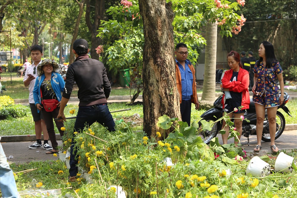 Thấy hai thanh niên đập bỏ hàng trăm chậu hoa, nhiều người đứng lại xem trong vẻ tiếc nuối vì đa phần chúng còn khá đẹp. Ảnh: Trường Sơn