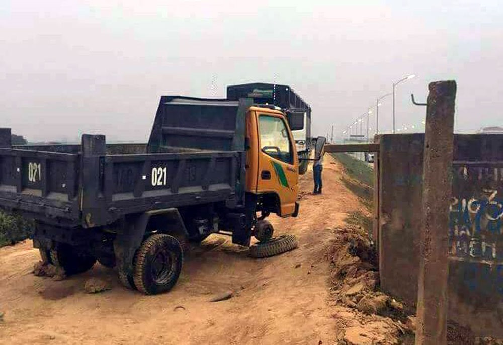 Một chiếc xe tải hỏng chắn ngang đê không đeo biển số, bị “tố” là dàn dựng.