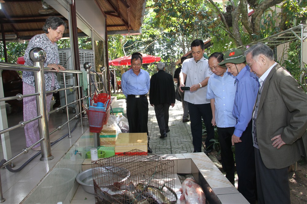 Ông Khải và mọi người bên hồ nuôi cá tại nhà ông Nguyễn Minh Triết. Ảnh: X.L