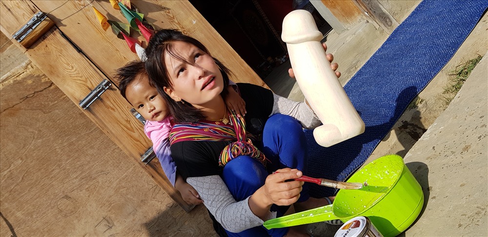 Người mẹ trẻ đang trang điểm một chiếc Linga bằng gỗ để làm đồ lưu niệm.