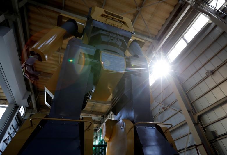 Kỹ sư Nagumo đang sử dụng dây cáp để lên buồng điều khiển robot Mononofu. (Ảnh: REUTERS)
