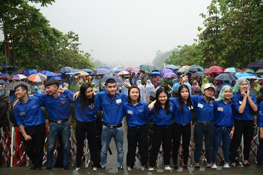 Đội ngũ thanh niên tình nguyện lập “hàng rào” trong mưa, ngăn dòng người trước giờ mở cửa đền. Anh Phạm Hoàng Tuấn ( Đội Thanh niên TN xã Phù Ninh, Phú Thọ) chia sẻ: “Chúng tôi làm công tác tình nguyện ở đây từ những ngày đầu khai hội. Tuy nhiên đây là buổi đầu tiên mưa lớn như thế này. Chúng tôi rất vui vì góp một phần phần tạo nên sự thành công lễ hội đền Hùng 2018 nên mưa lớn cũng không nề hà.”