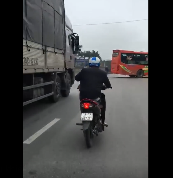 Nam thanh niên dùng 2 chân điều khiển xe máy, sử dụng điện thoại trên quốc lộ 1A. Ảnh: Cắt từ clip