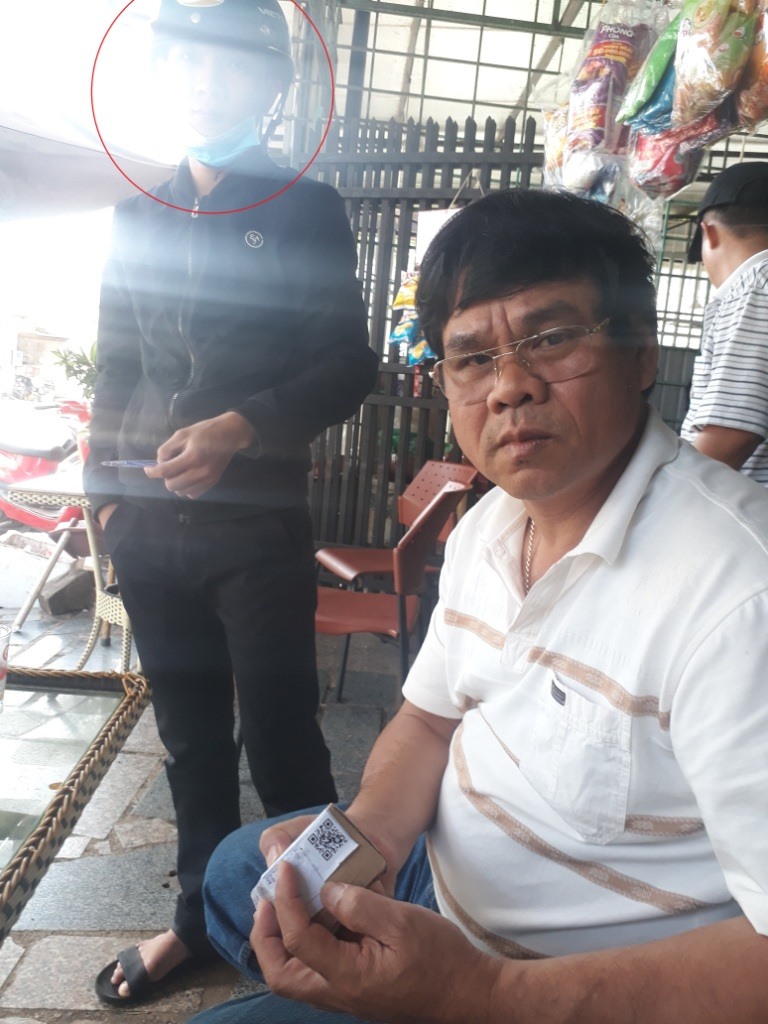 Đại tá Hồi cùng gói bưu phẩm không đặt mua và người chuyển hàng (khoanh đỏ). Ảnh Đình Văn.