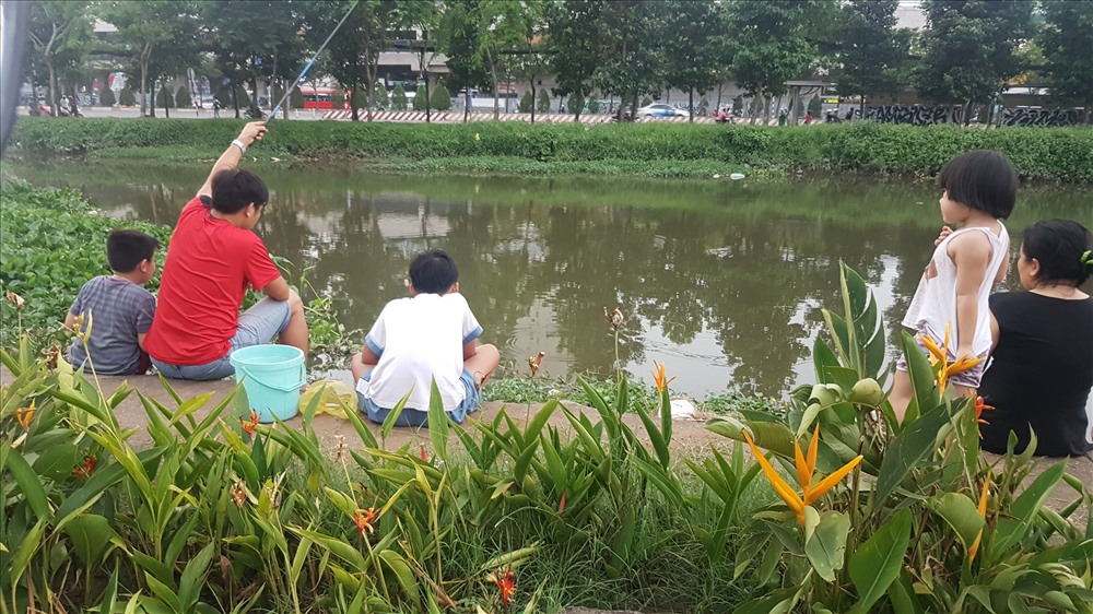 Thậm chí, nhiều gia đình còn đưa cả các cháu nhỏ ra kênh này vui chơi, trong khi người lớn thì mải mê câu cá. Điều đáng nói là dòng kênh này rất sâu, lại chưa có lan can ngăn cách nên nguy cơ các cháu nhỏ bị sự cố là rất cao. Ảnh: Trường Sơn