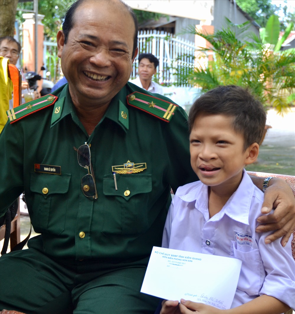 Thiếu tá Danh Lê Quyền trao tiền hỗ trợ cho học sinh Lâm Chí Thừa (SN 2009, ấp Bãi Nhà A, xã Lại Sơn) bị dị tật bẩm sinh, mồ côi cha, sống với nội. (Ảnh: Lục Tùng)