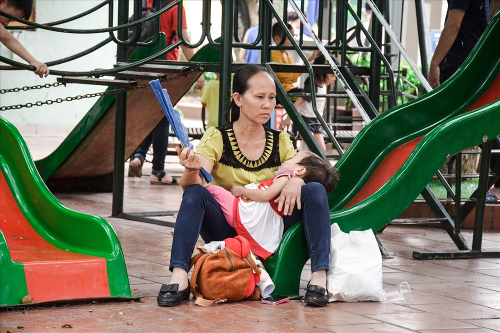 Thời tiết nắng nóng, người phụ nữ mệt mỏi chờ đến lượt cháu mình khám.