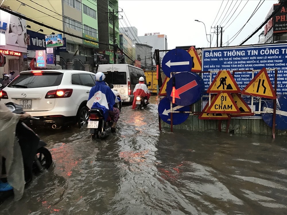 Một đoạn Nguyễn Xí đang được rào chắn để thi công công, cộng với tình trạng nước ngập nước đã khiến giao thông qua khu vực này gặp rất nhiều khó khăn.