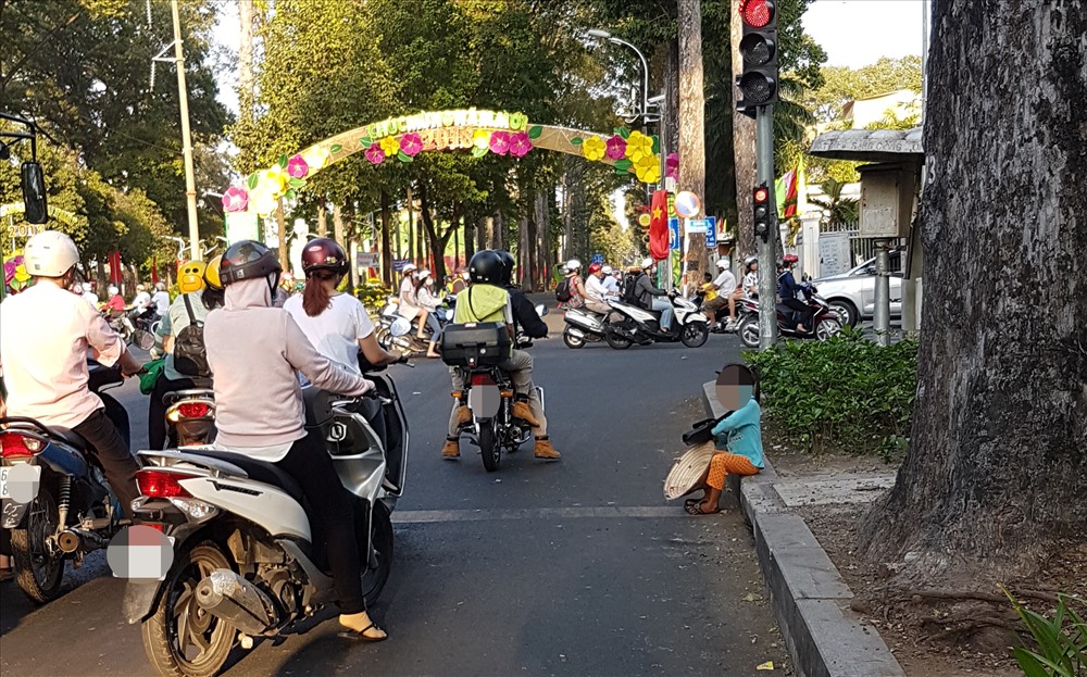 Bé gái ngồi chờ đèn đỏ trên đường Kinh Dương Vương để xin ăn mà PV ghi nhận được. Ảnh: T.S