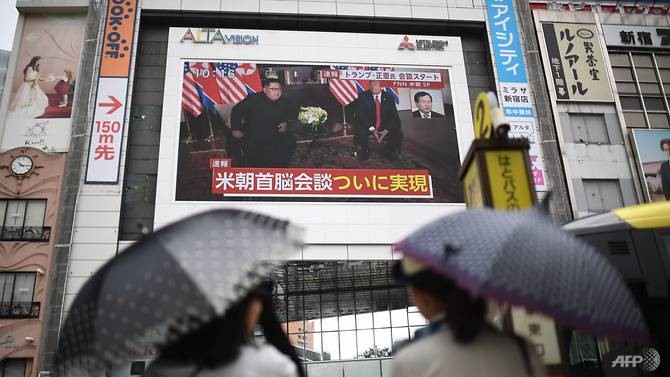 Người đi bộ trên đường phố Nhật Bản theo dõi bản tin về cuộc họp giữa lãnh đạo Triều Tiên Kim Jong-un và Tổng thống Mỹ Donald Trump. Ảnh: AFP.