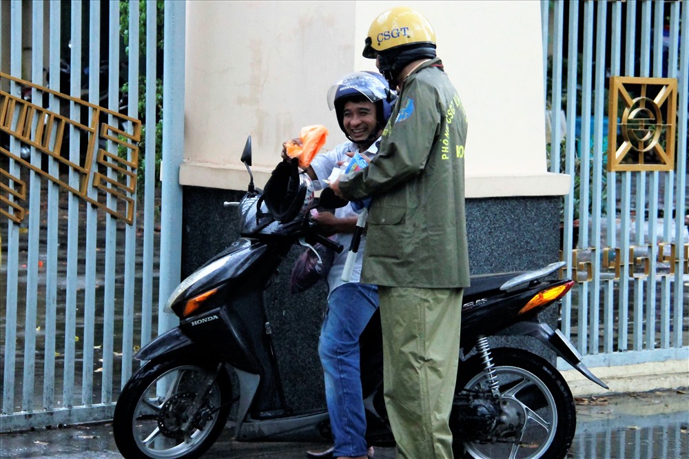 CSGT phát áo mưa miễn phí cho phụ huynh đang đọi mưa chờ con em mình trước các điểm thi PTTH quốc gia. Ảnh: T.S