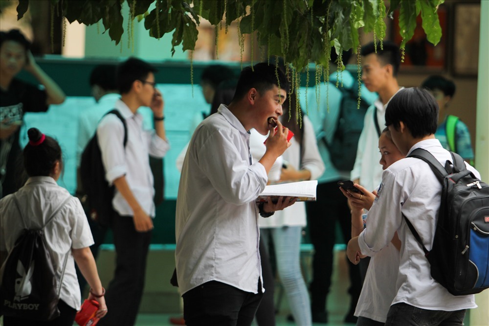 Một thí sinh ăn vội miếng bánh trước khi bước vào bài thi môn Ngữ văn. (Ảnh: Tô Thế).