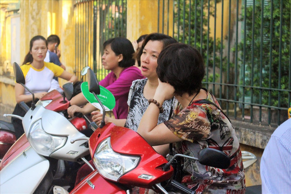 Nhiều ông bố bà mẹ ngồi trên xe máy chờ con.
