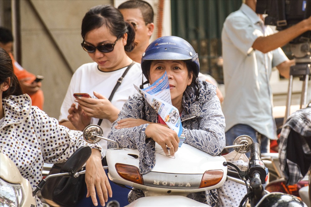 Người phụ nữ dùng tờ giấy để làm quạt chống trọi với cái nắng.