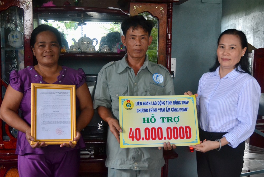Phó chủ tịch LĐLĐ Đồng Tháp Đặng Thị Kim Đang (phải ảnh) trao quyết định và bảng tượng trưng mức hỗ trợ MÂCĐ cho gia đình anh Lê Văn Êm. (Ảnh: Lục Tùng)