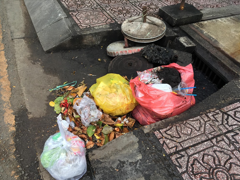 Rác và các mãng be tông bịt kín miệng thoát nước trên đường Hoàng Sa, Q.1.
