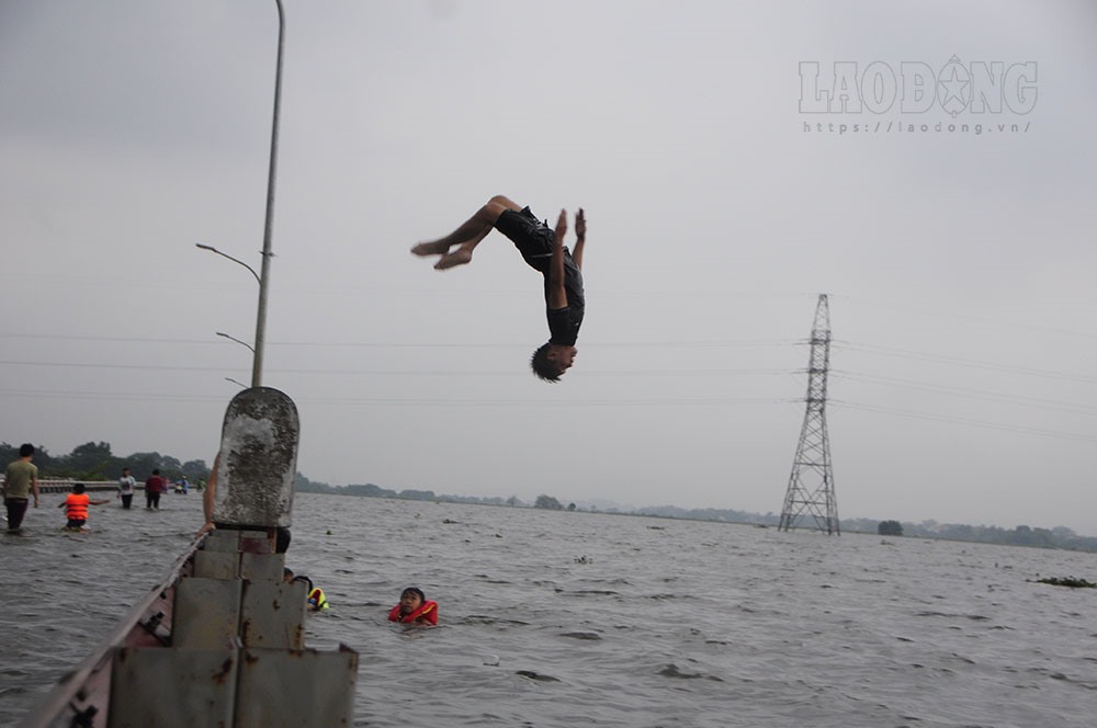 Nhiều thanh niên còn đứng trên khu vực dải phân cách của đường để thực hiện những cú nhảy nhào lộn với dòng nước trên ruộng.