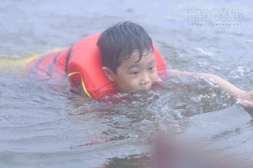 Nhiều trẻ được trang bị cả áo phao để tập bơi ngay trên đường và cánh đồng ngập nước.