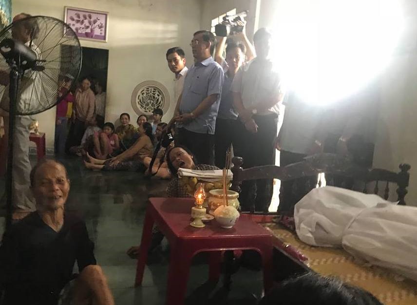 Bàn thờ được đặt tạm trên chiếc bàn, bên cạnh là thi thể nạn nhân và những người thân khóc ngất vì thương tiếc. Ảnh: TH.