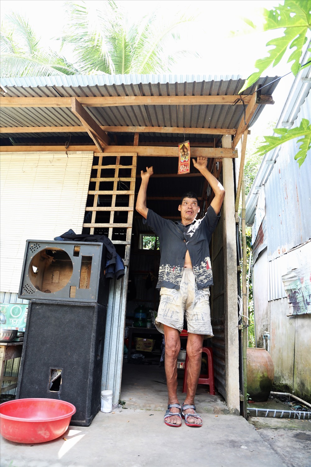 Ông Y trước ngôi nhà đơn sơ mà những người làm từ thiện gom tiền giúp để ông có chỗ chui ra chui vào. Ảnh: Trường Sơn