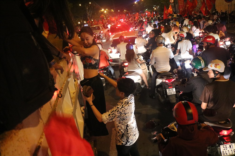 Còn cô gái này thì không ngại giày cao gót và chiếc áo có phần “khó xử” của mình, vẫn hăng hái trèo lên thùng xe tải để cổ vũ cho sung