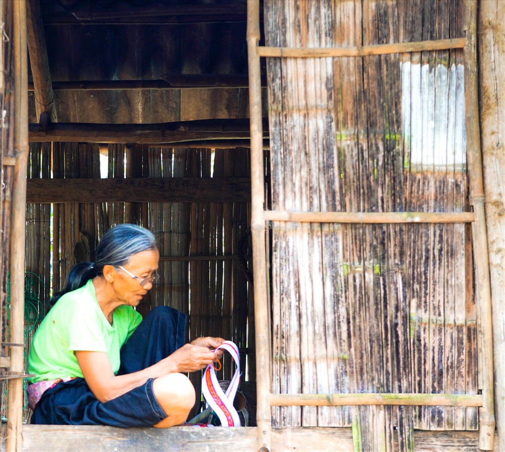 Bà mế Mường này đã 84 tuổi đang ngồi khâu vá bên cửa nhà.