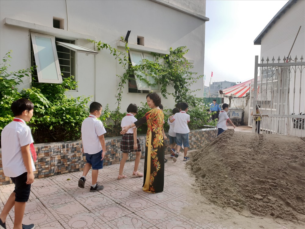 Học sinh phải bước qua các đống cát để di chuyển ra, vào cổng trường. Ảnh: HN