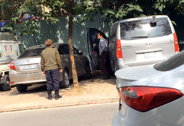 Một bảo vệ đứng ngóng khách xuống xe để thu tiền