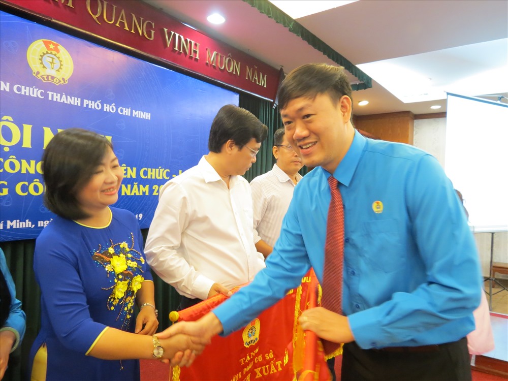 Ông Lương Tuấn Anh tặng cờ thi đua xuất sắc của LĐLĐ TPHCM cho các đơn vị trực thuộc - Ảnh: L.T