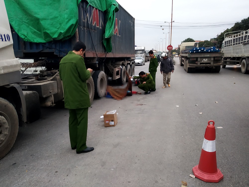 Cú va chạm với xe container khiến 2 người ngồi trên xe máy ngã xuống đường và tử vong tại chỗ. Ảnh: HH.