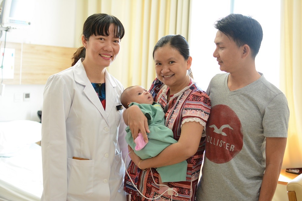 Bé Nguyễn Đặng Khôi Nguyên trong vòng tay của cha mẹ và bác sĩ Hồ Thị Xuân Nga khi xuất viện.