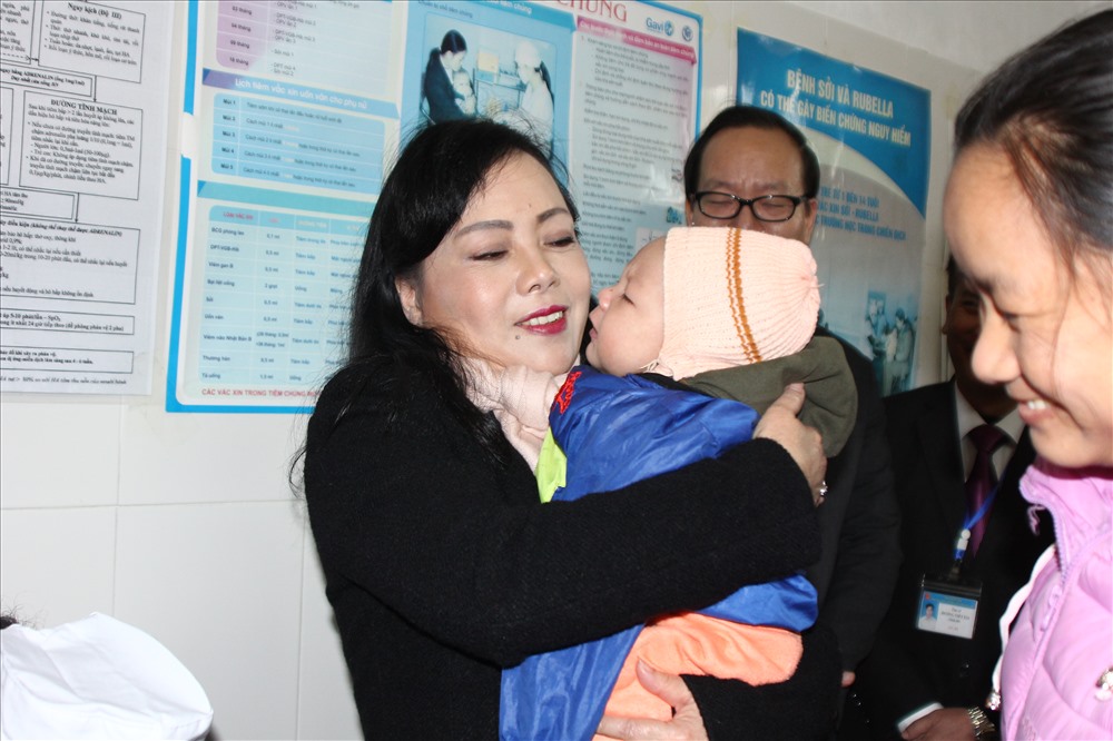 Bộ trưởng Tiến dỗ dành, cưng nựng các bé sau khi kiểm tra công tác tiêm phòng vắc xin ComBE Five. Ảnh: Thùy Linh